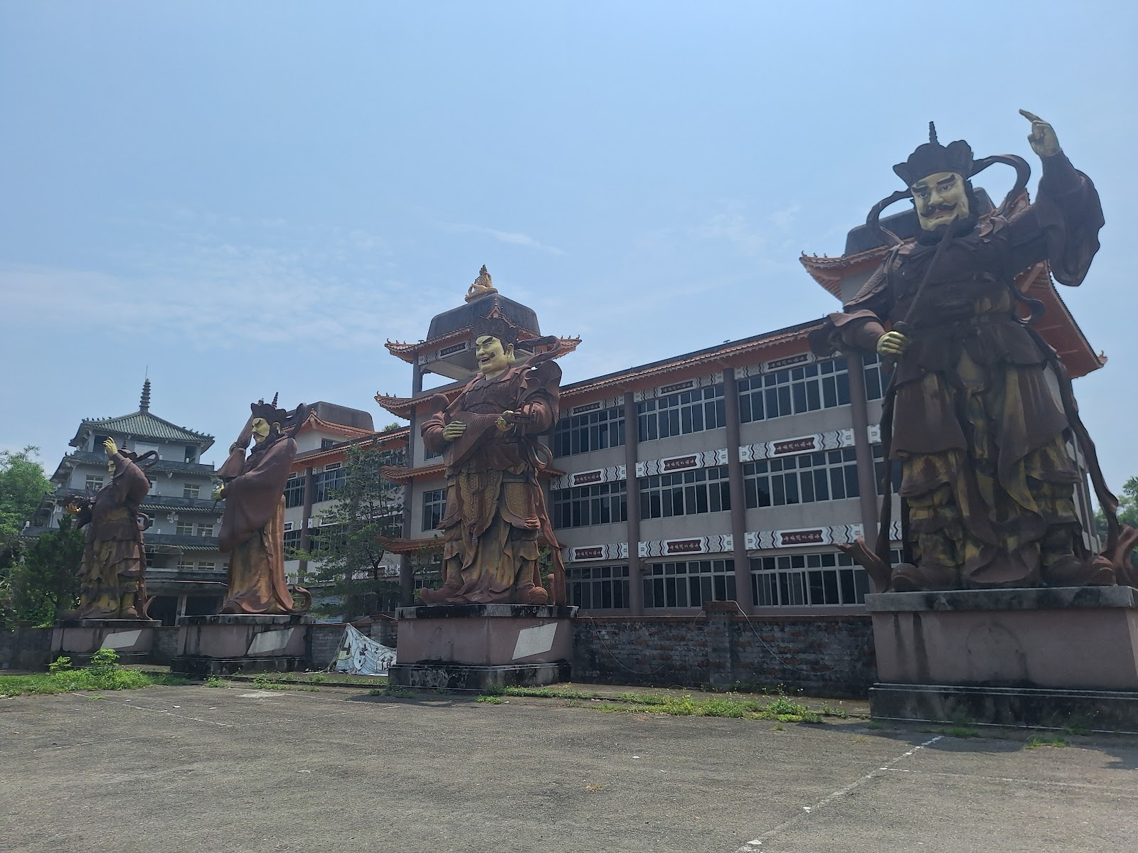 湖山寺廣場巨型四大天王雕像，色彩鮮豔佇立於廢棄建築前