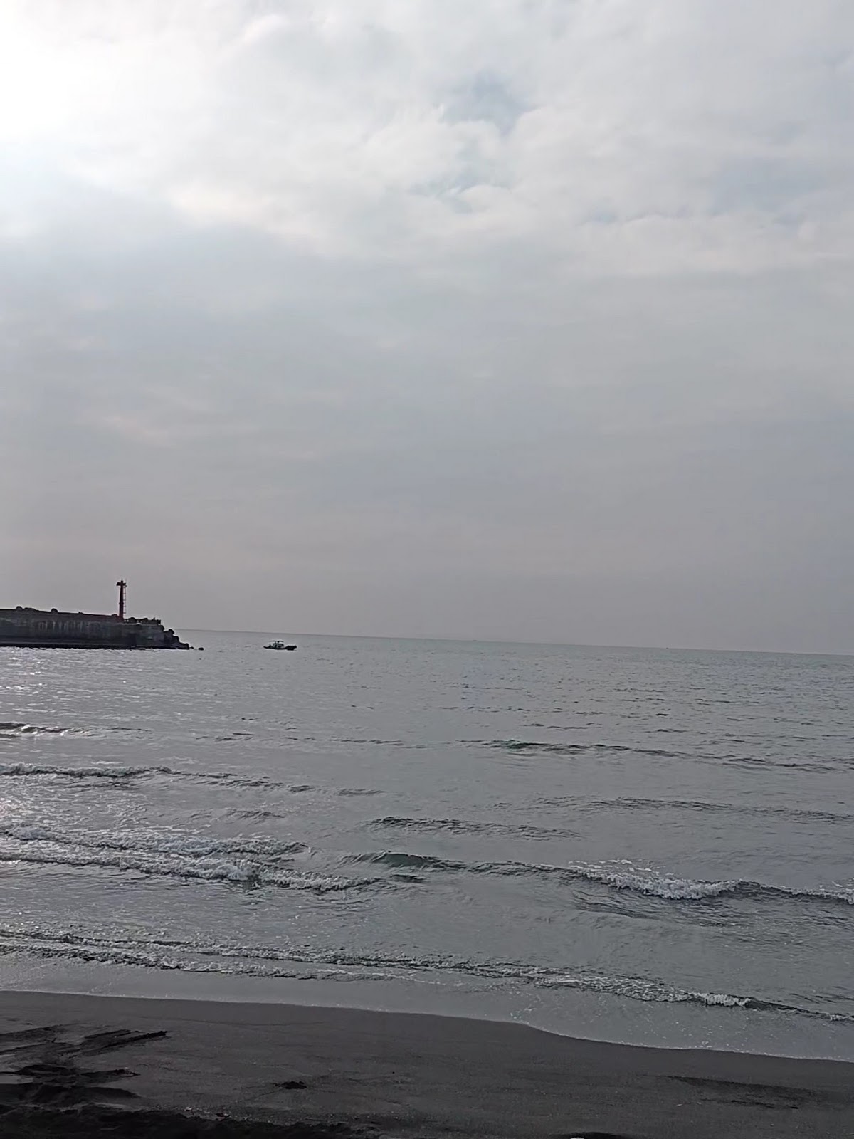 老人海沙灘黑沙與浪花遠眺枋寮漁港燈塔