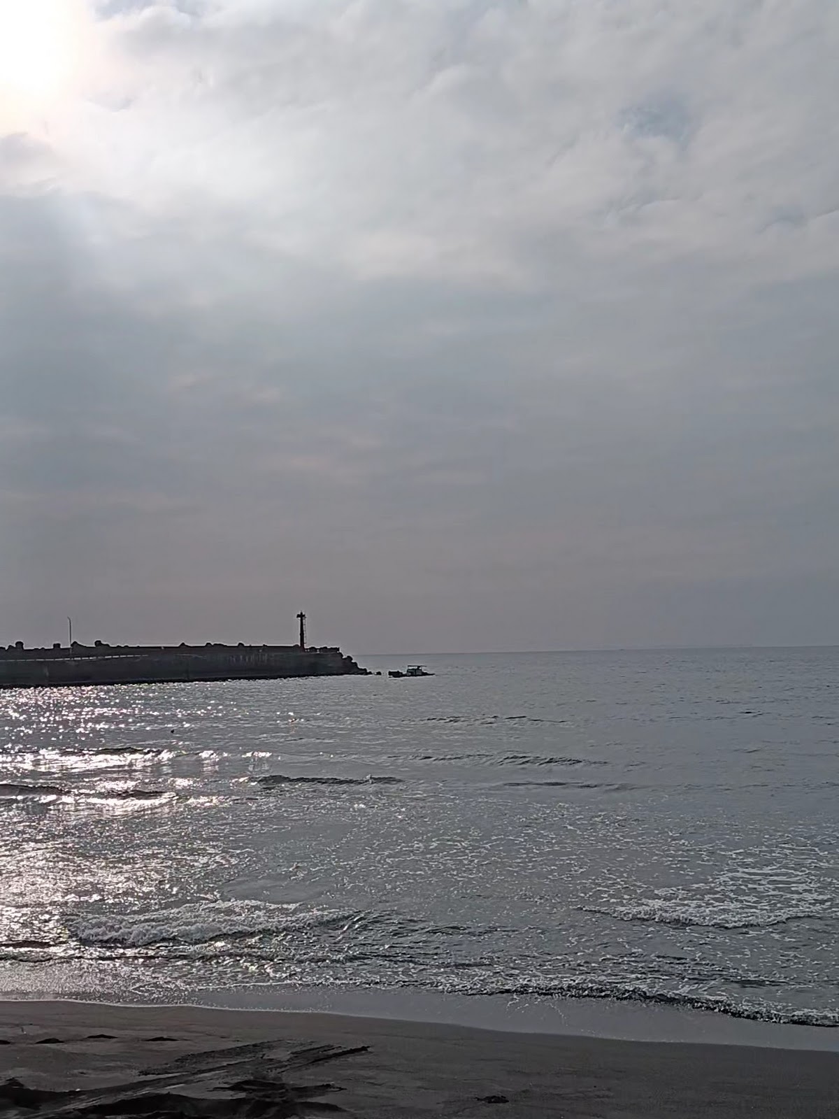 夕陽下老人海沙灘海浪拍打黑沙礫石