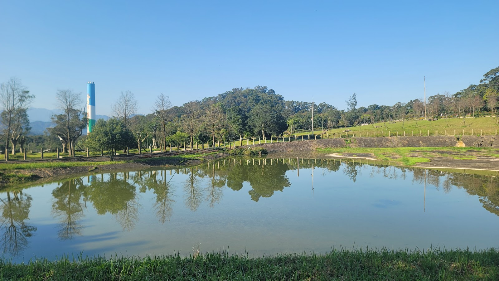 福德坑環保復育公園生態池湖面倒影藍白相間煙囪地標