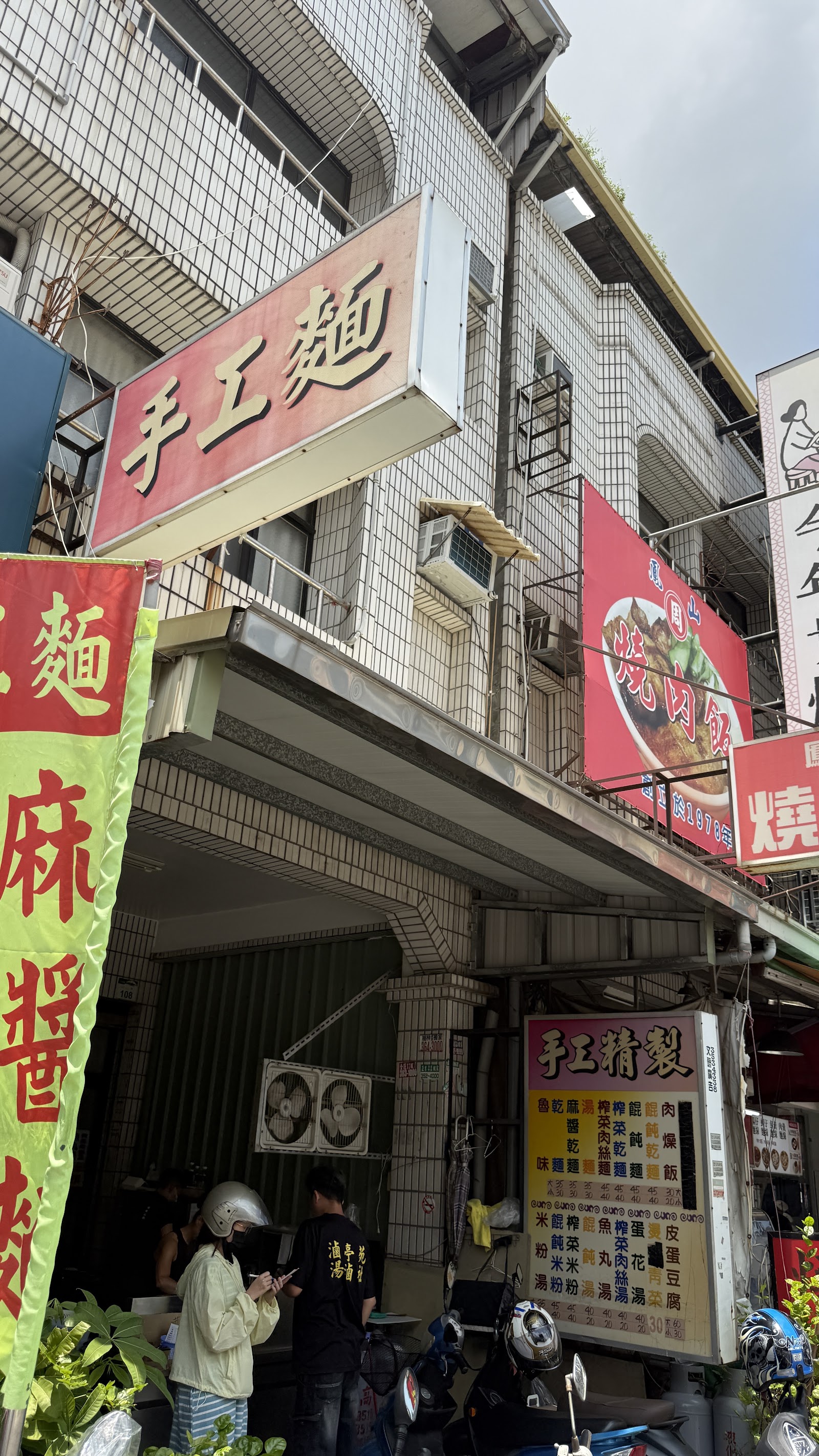 高雄大社手工麵店面招牌，紅底黃字手工麵字樣與麻醬麵布條
