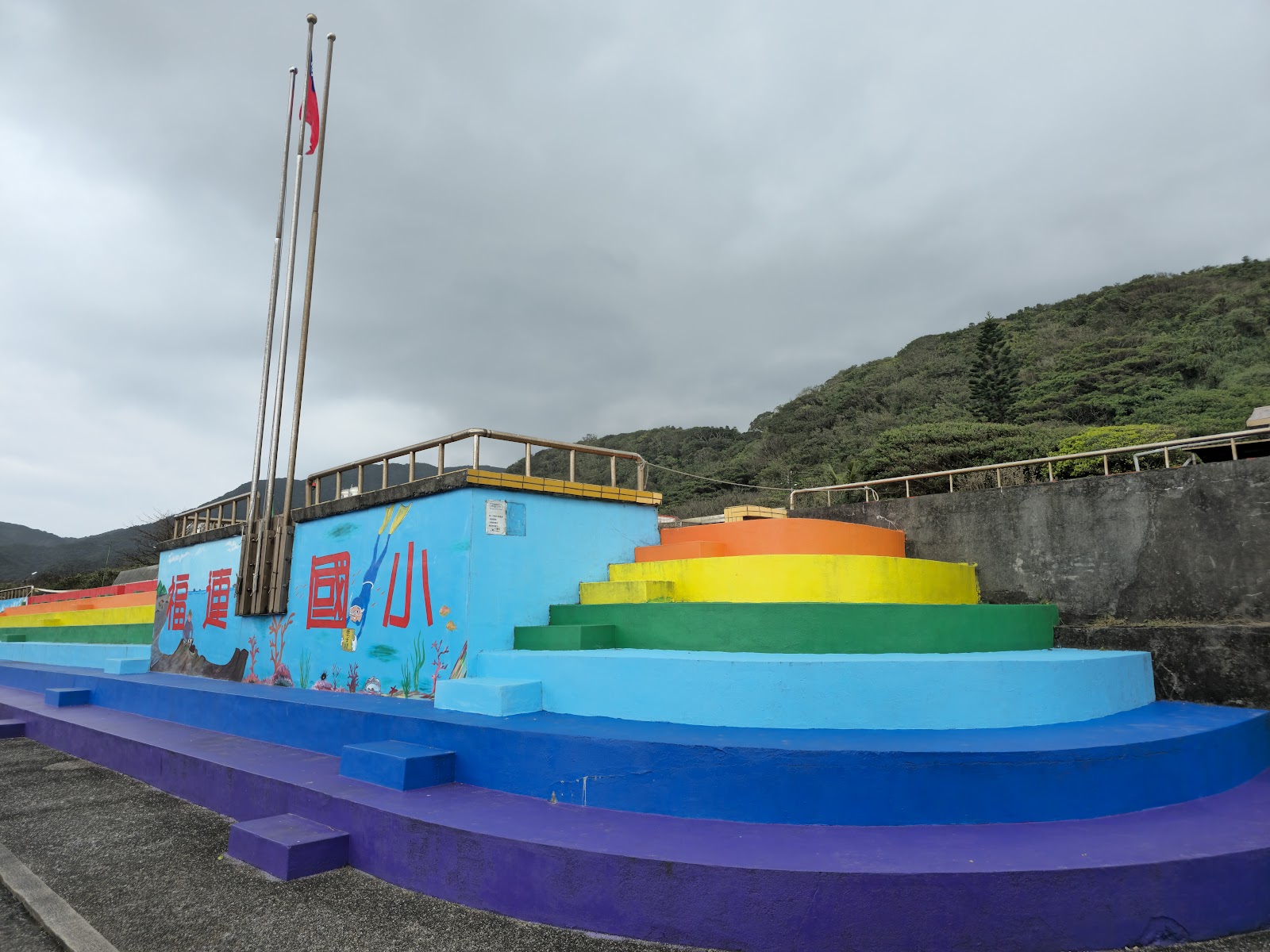 新北市貢寮區福連國民小學彩虹階梯造型外牆，天空藍橘黃綠漸層色彩