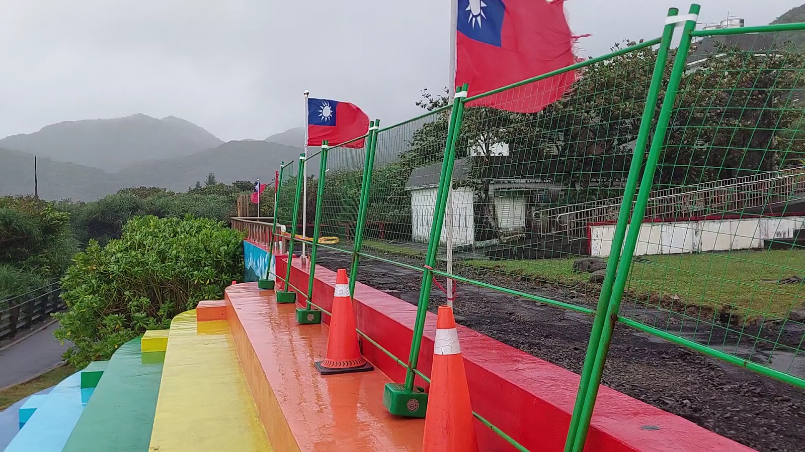 福連國小操場旁彩虹色護欄與飄揚國旗，遠景山巒雲霧