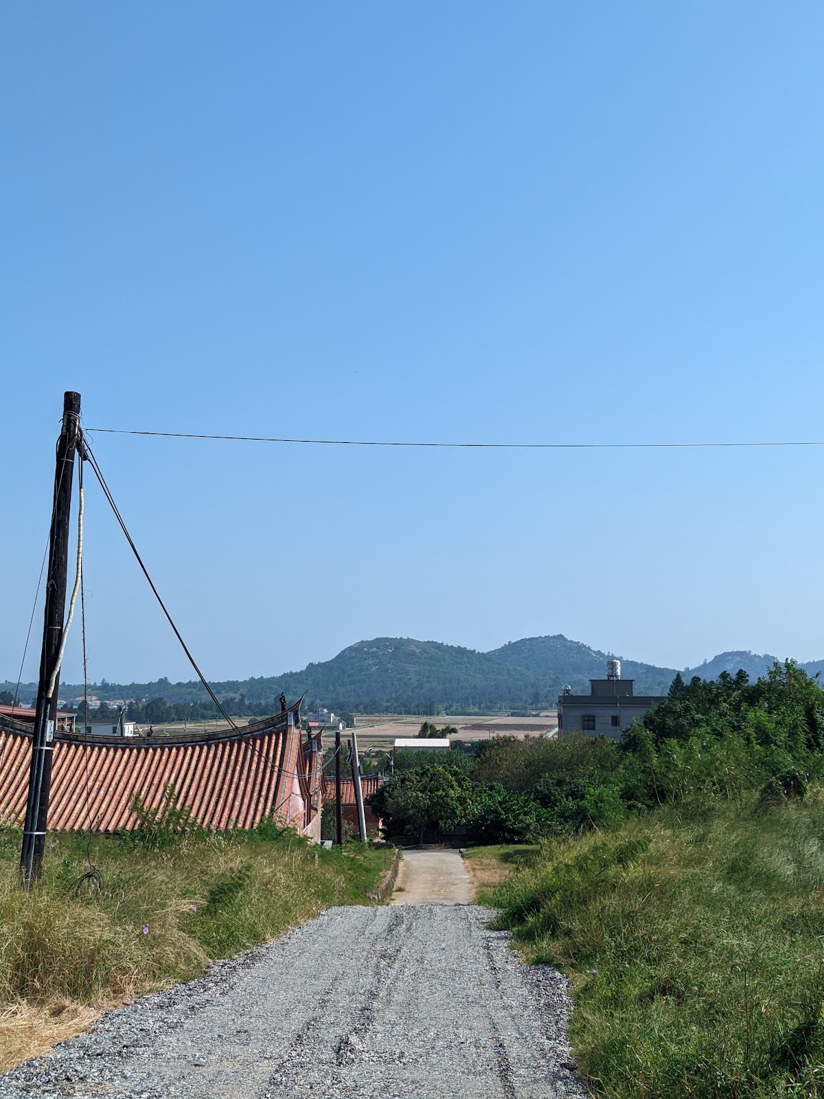 官澳聚落田間石子小路,遠方可見太武山稜線與紅瓦燕尾脊古厝
