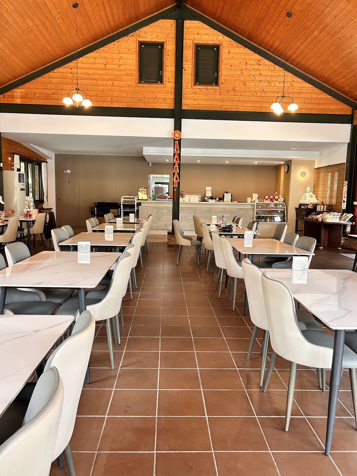 挑高木質屋頂的室內用餐區,大理石紋餐桌整齊排列