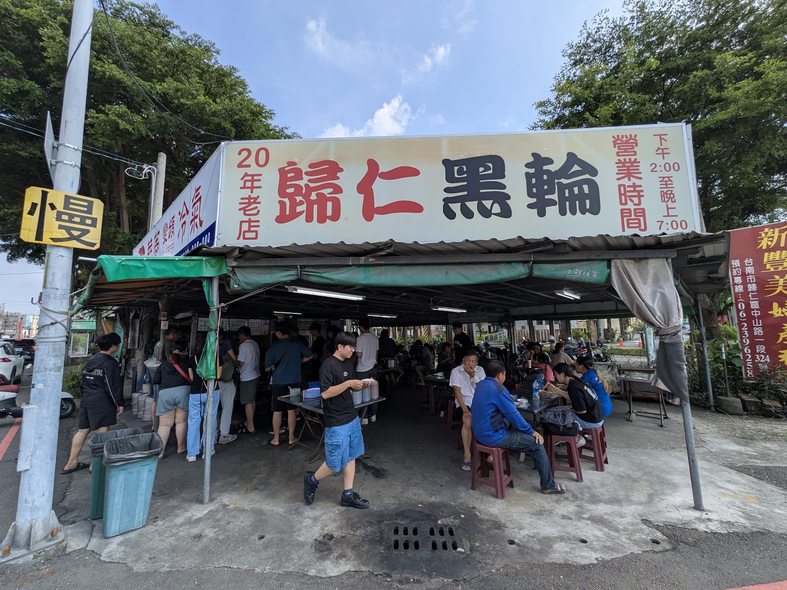 歸仁黑輪攤位全景,招牌寫著20年老店,顧客在棚下用餐