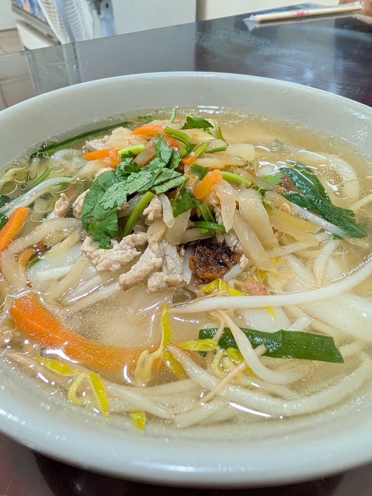 湯粄條上桌,鋪滿豆芽菜、肉絲與香菜,湯頭清澈