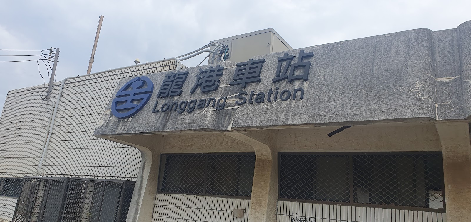 龍港車站站體招牌特寫,水泥建築外牆寫著龍港車站與Longgang Station