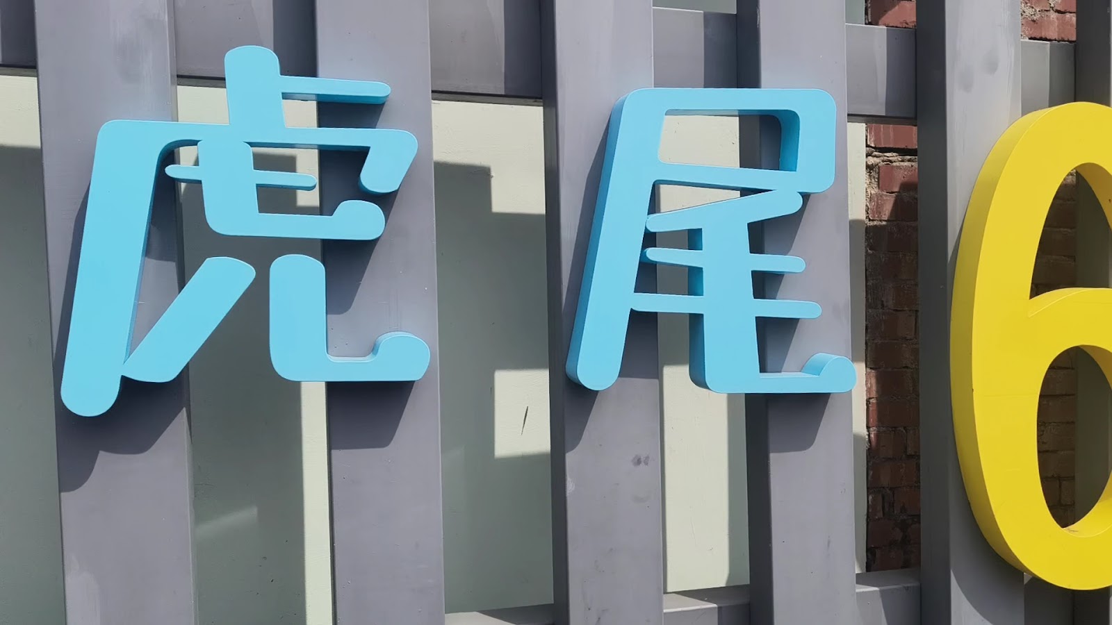 虎尾632高地公園&水樂園－「虎尾」兩字天藍色立體字招牌特寫，灰色木柵欄背景