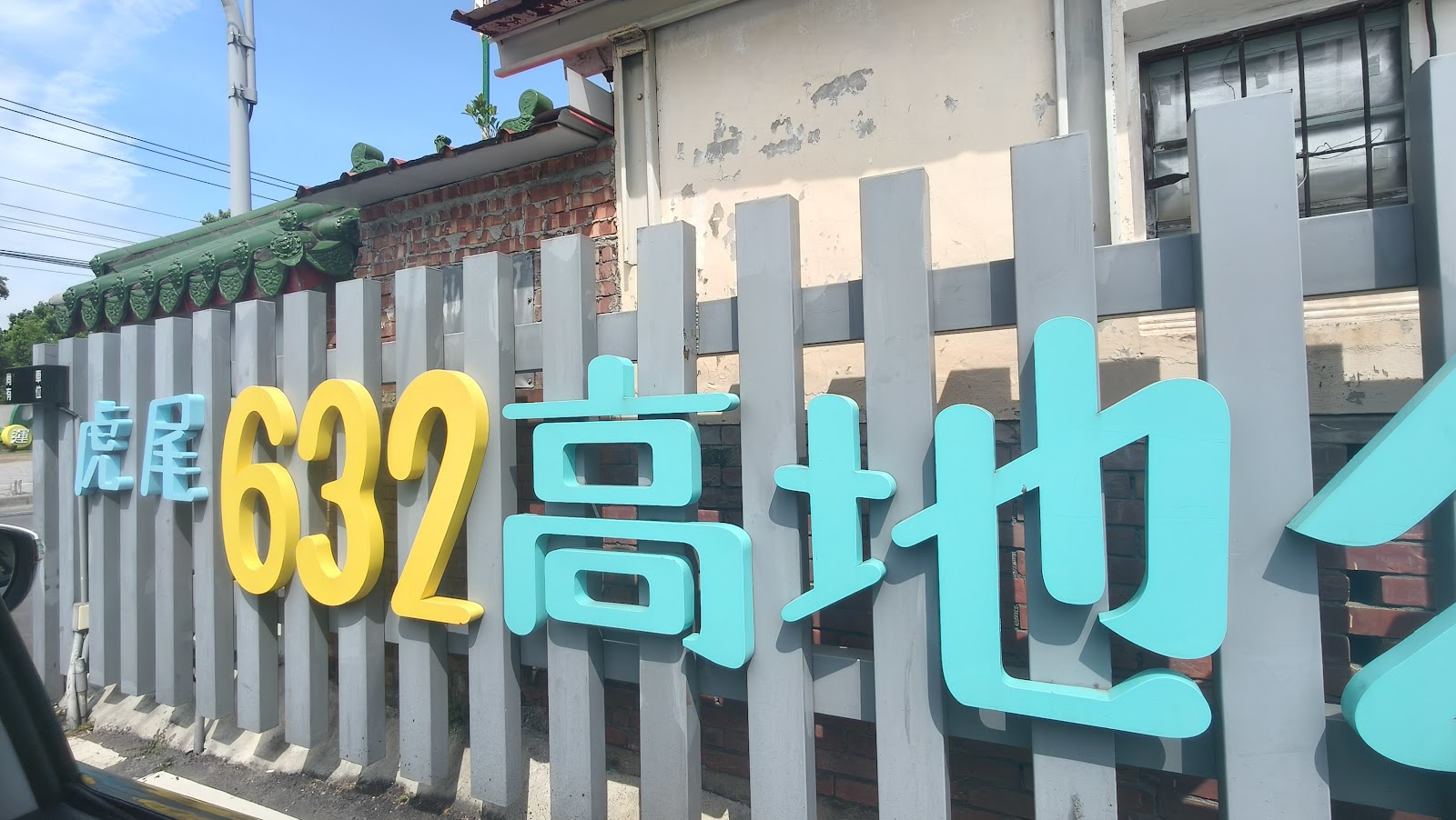 虎尾632高地公園&水樂園－「虎尾632高地」全名招牌，天藍黃配色立體字，紅磚老屋背景