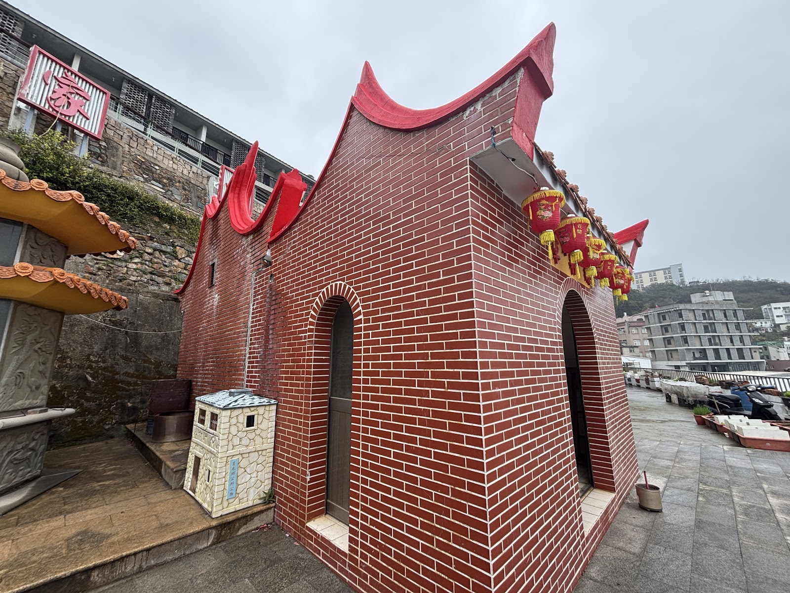 胡將軍廟側面雙拱門建築,背景為青帆村山坡民宅