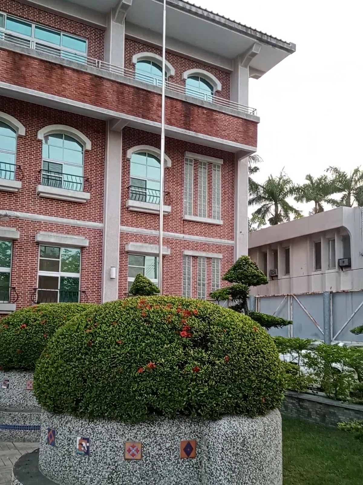 大林鎮公所前庭盆栽造景與旗杆,紅磚建築立面在藍天下格外醒目