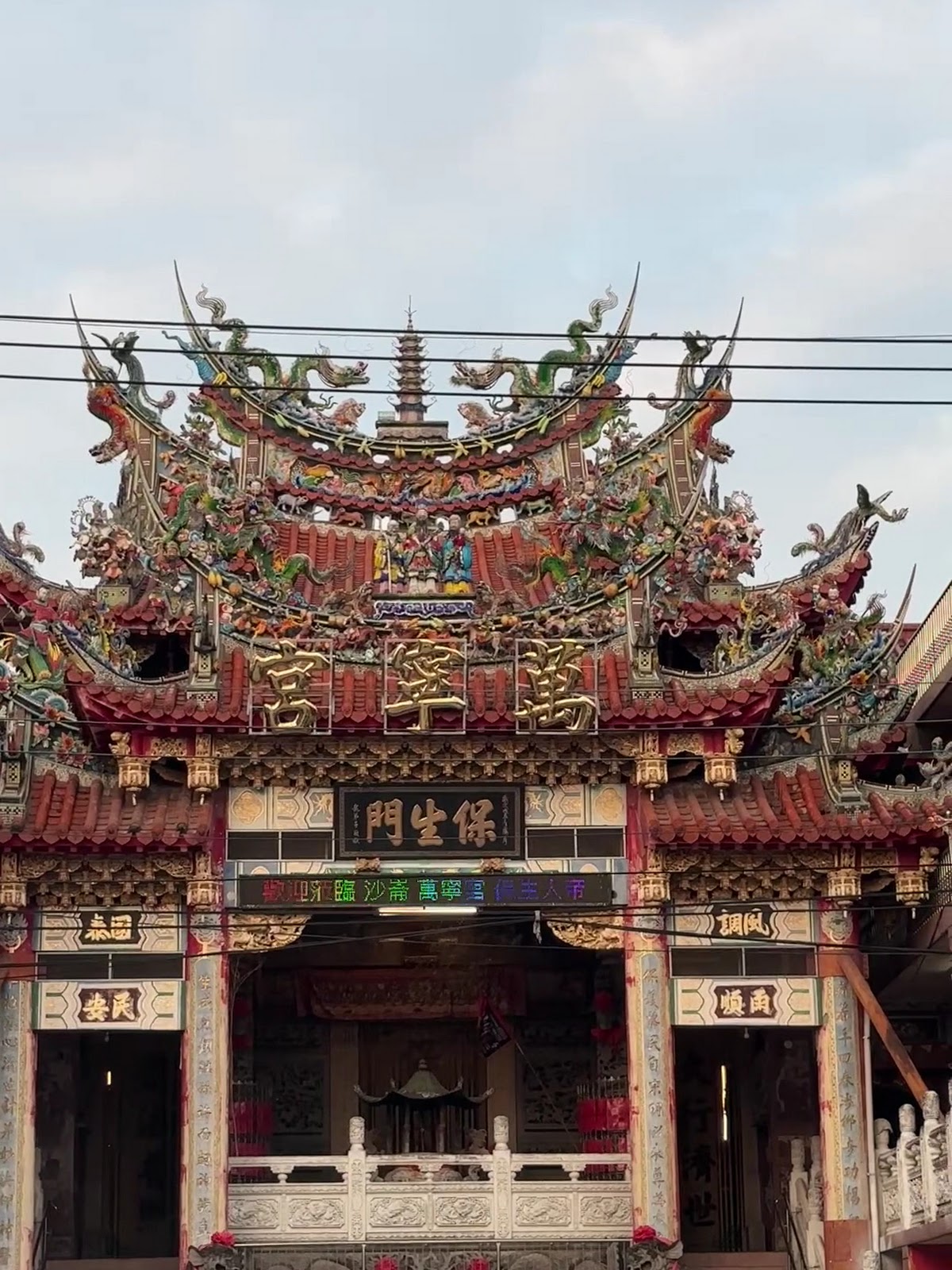 萬寧宮正門近照,「保生門」匾額與屋脊上層層交疊的剪黏裝飾清晰可見