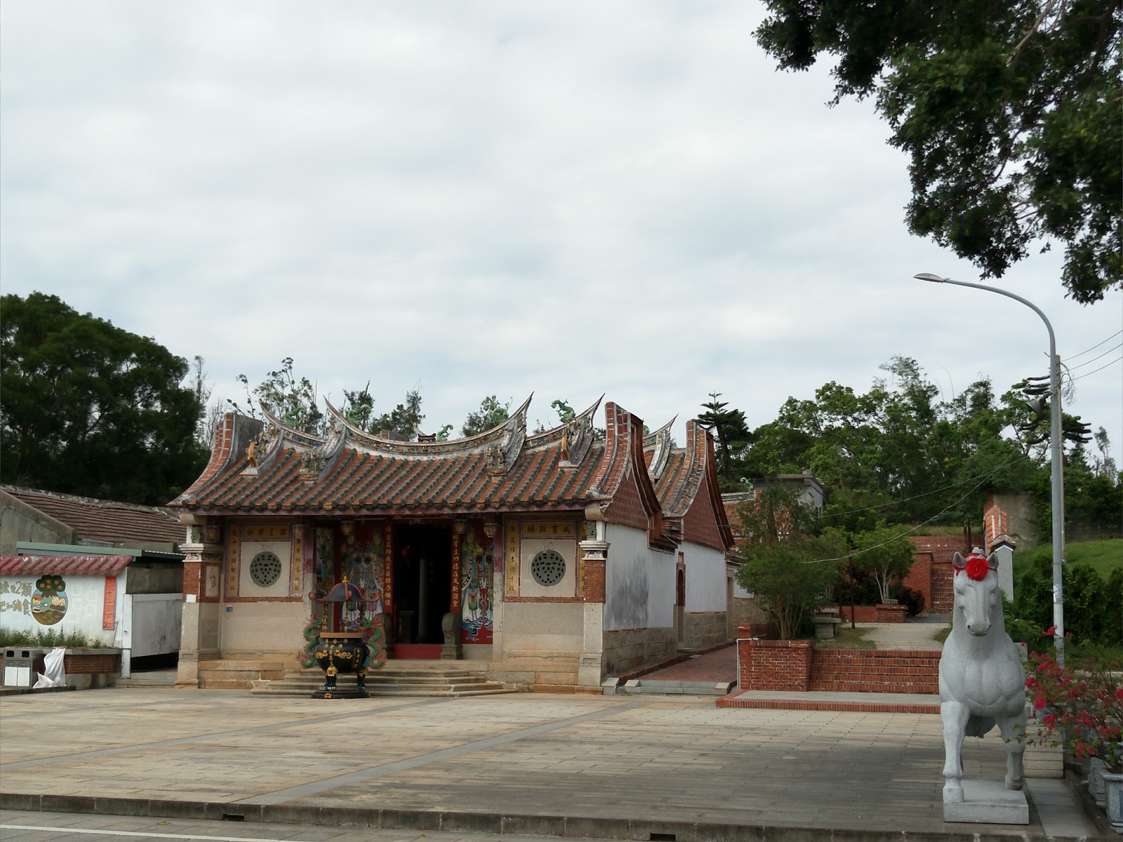 金門金城鎮豐蓮山牧馬侯祠 - 廟宇燕尾脊全景與白色石馬,陰天別有一番古