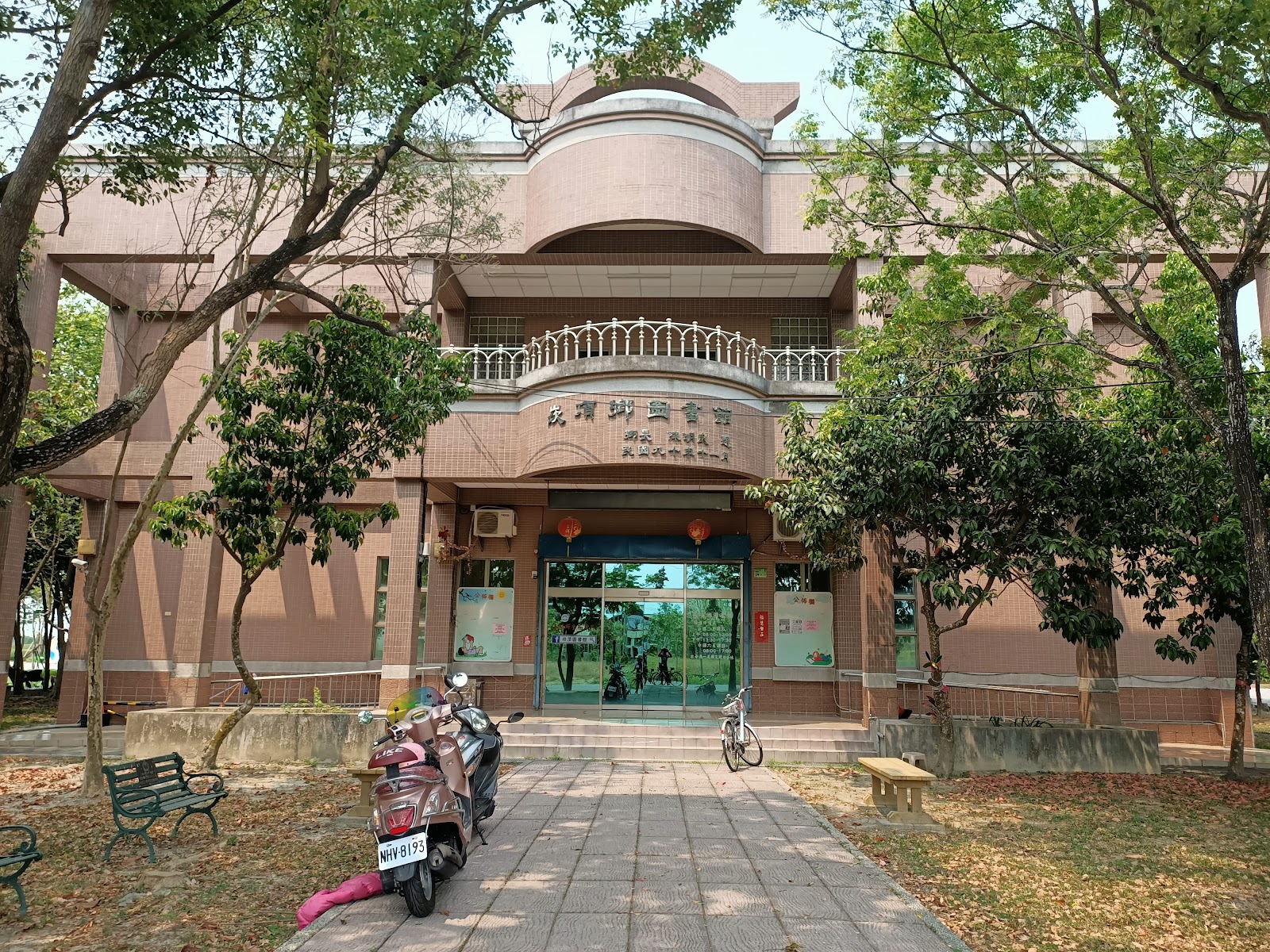 崁頂鄉立圖書館粉橘色弧形外觀,老樹環繞的建築正面