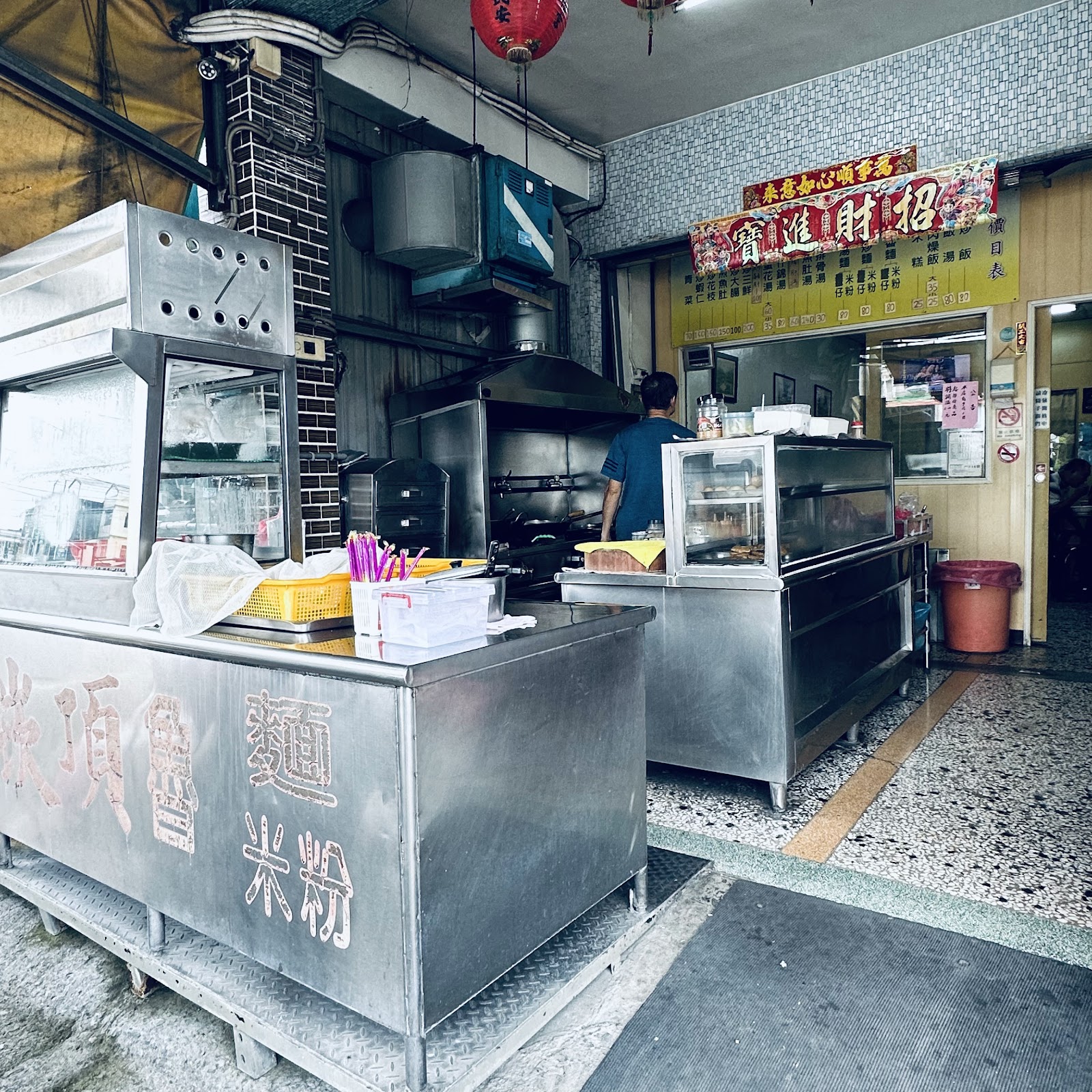 崁頂魯米粉店面不鏽鋼料理工作檯,刻字招牌與店內忙碌景象