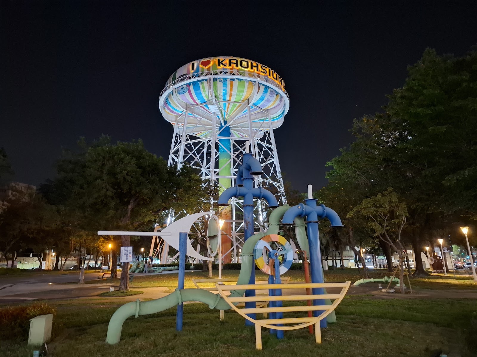 自來水公園夜間點燈的遊戲區水管裝置與遠方水塔
