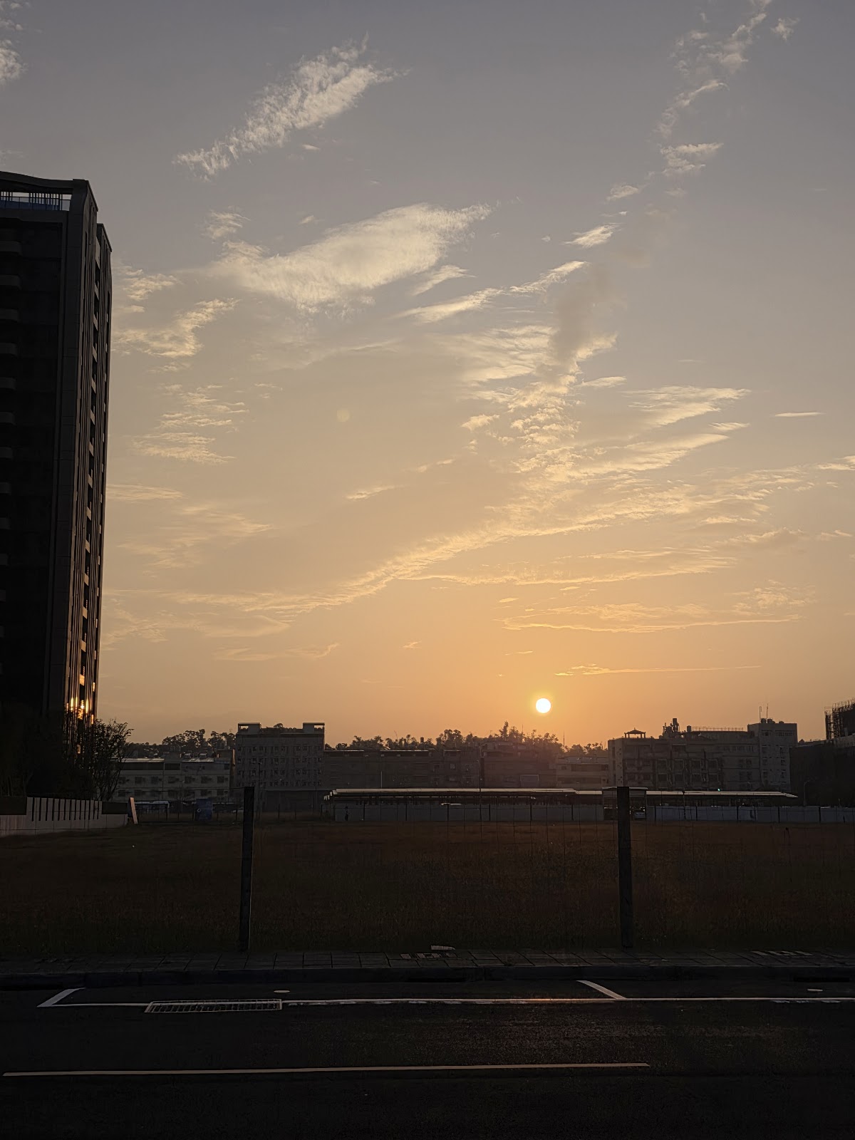 小港森林公園夕陽沉入大樓與草坪之間染紅天空