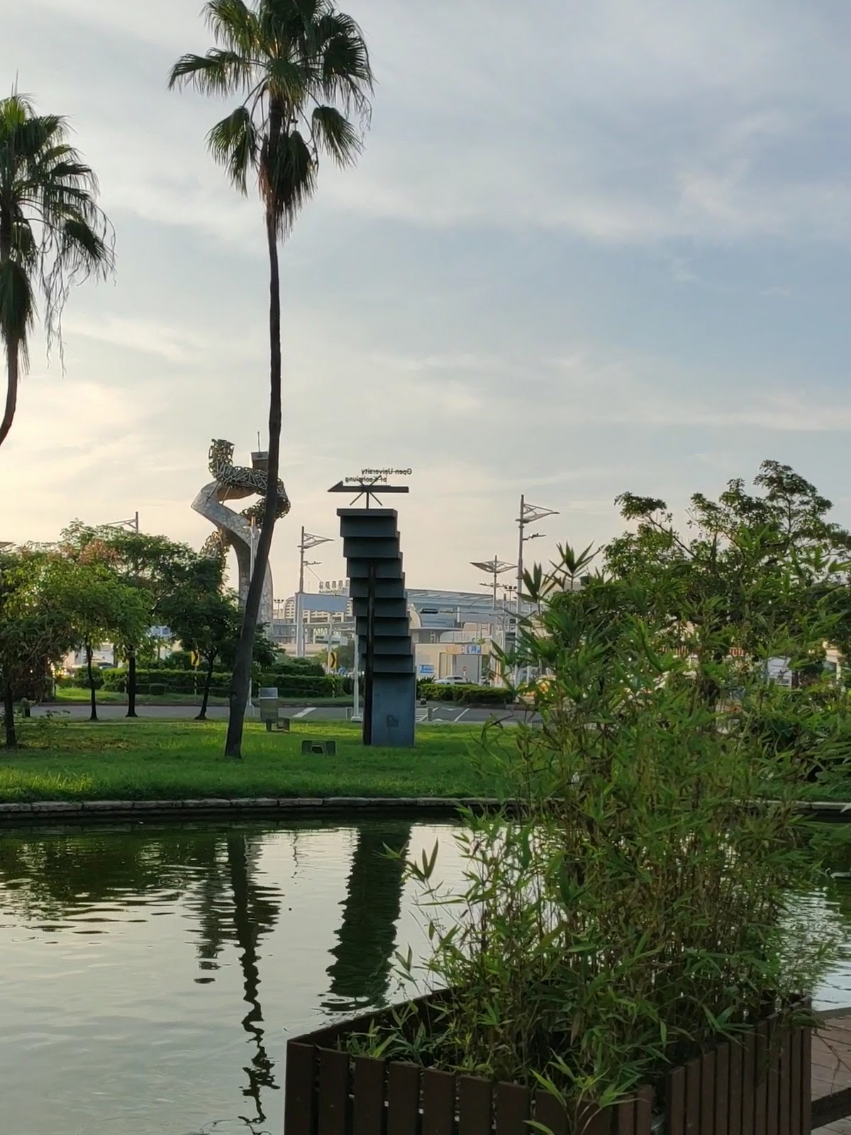 高雄公園生態池畔的現代雕塑與高聳大王椰子