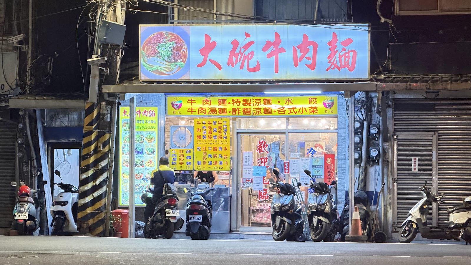 大碗牛肉麵店面夜景，紅底藍字招牌燈箱