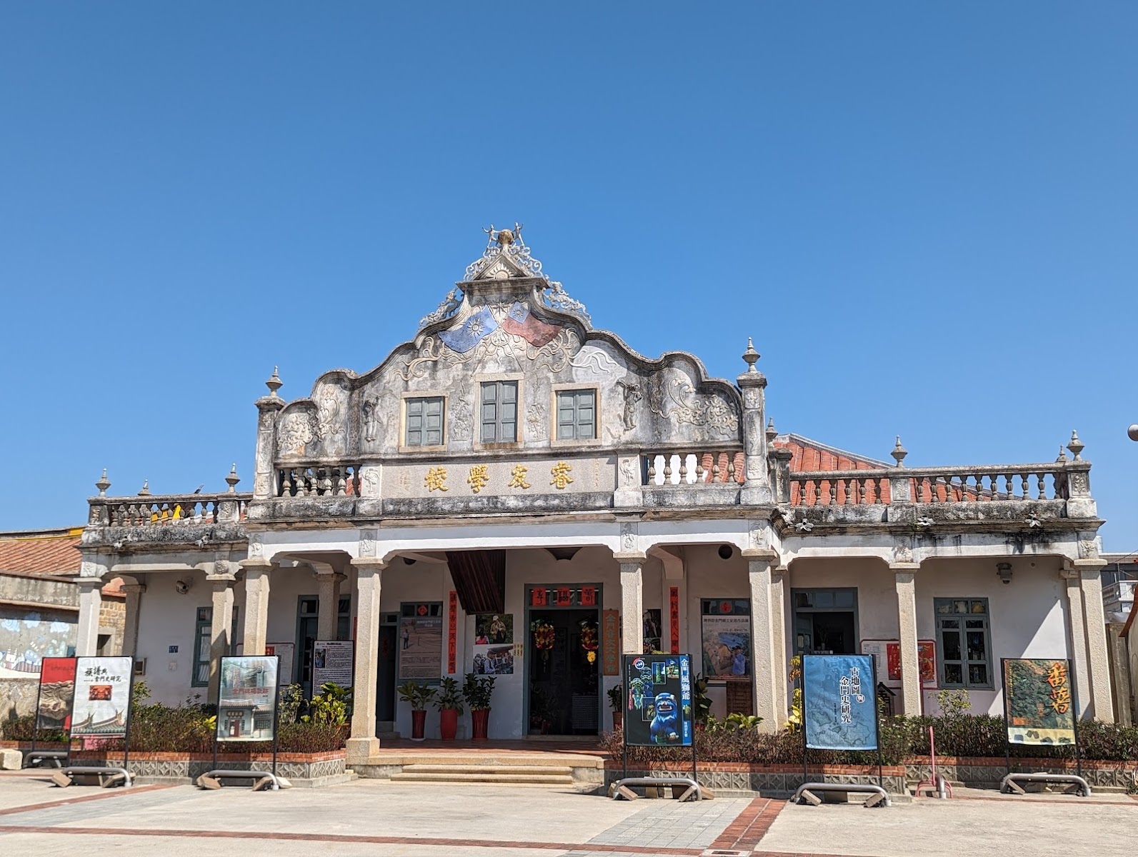 睿友學校正立面，巴洛克山頭與金色校名匾額，門前展示解說看板