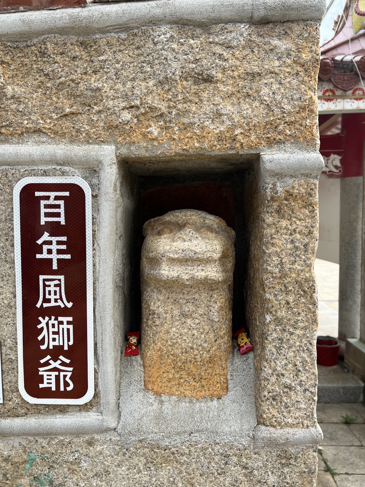 西方百年風獅爺嵌於牆面壁龕中，掛有「百年風獅爺」石牌