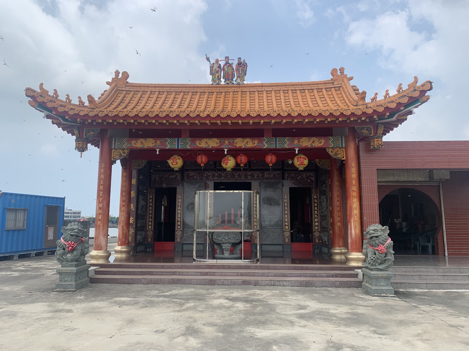 聖母宮正面，橙色屋瓦與石獅守衛，緊鄰漁港