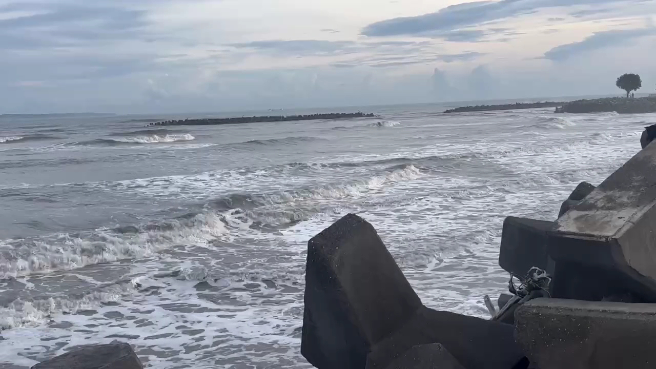 陰天海浪拍打消波塊，白色浪花