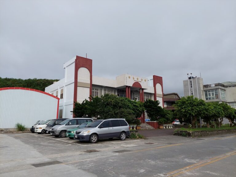 綠島鄉公所側面建築與停車場，陰天多雲，數輛汽車停放於前方