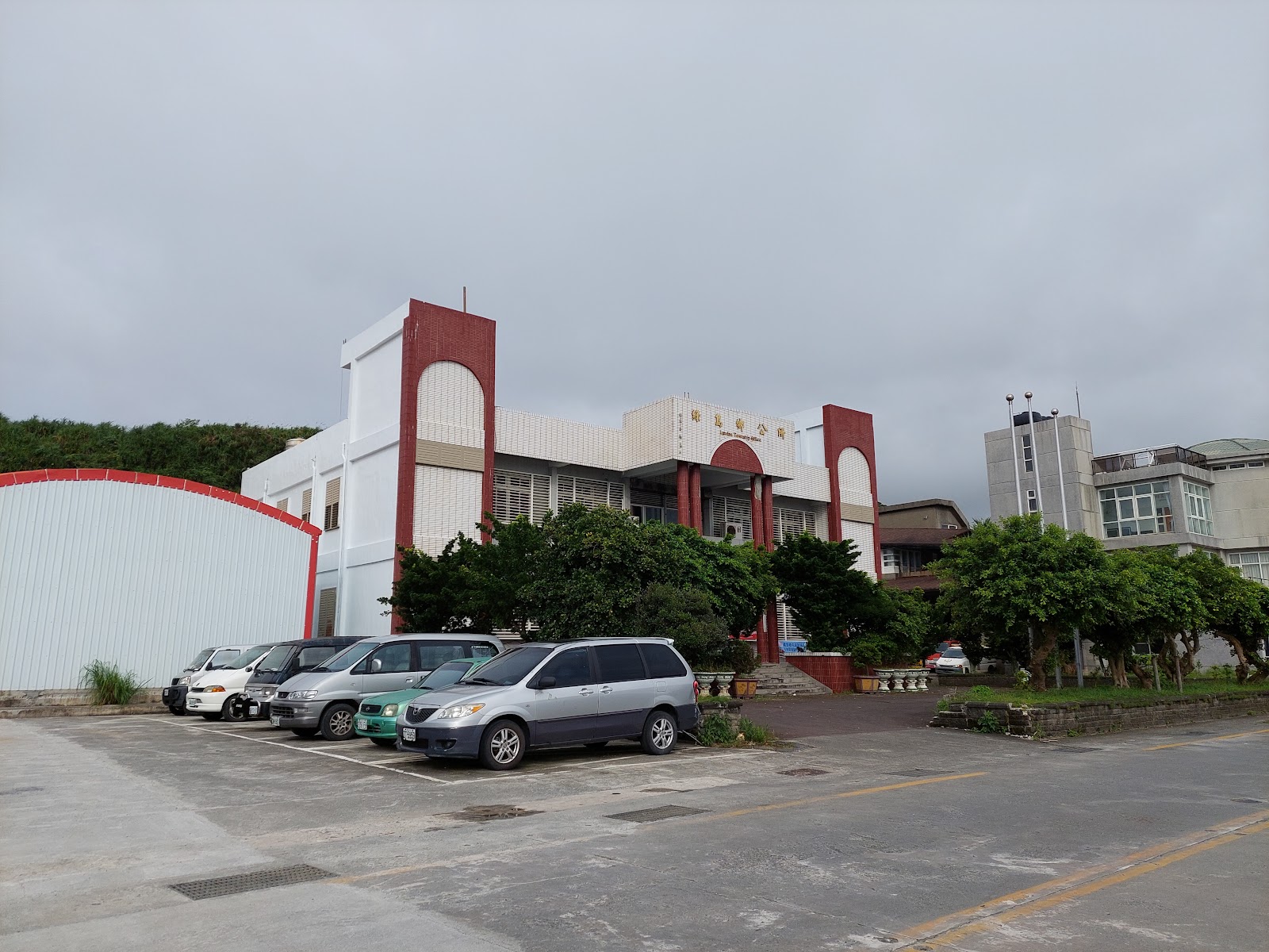 綠島鄉公所側面建築與停車場,陰天多雲,數輛汽車停放於前方