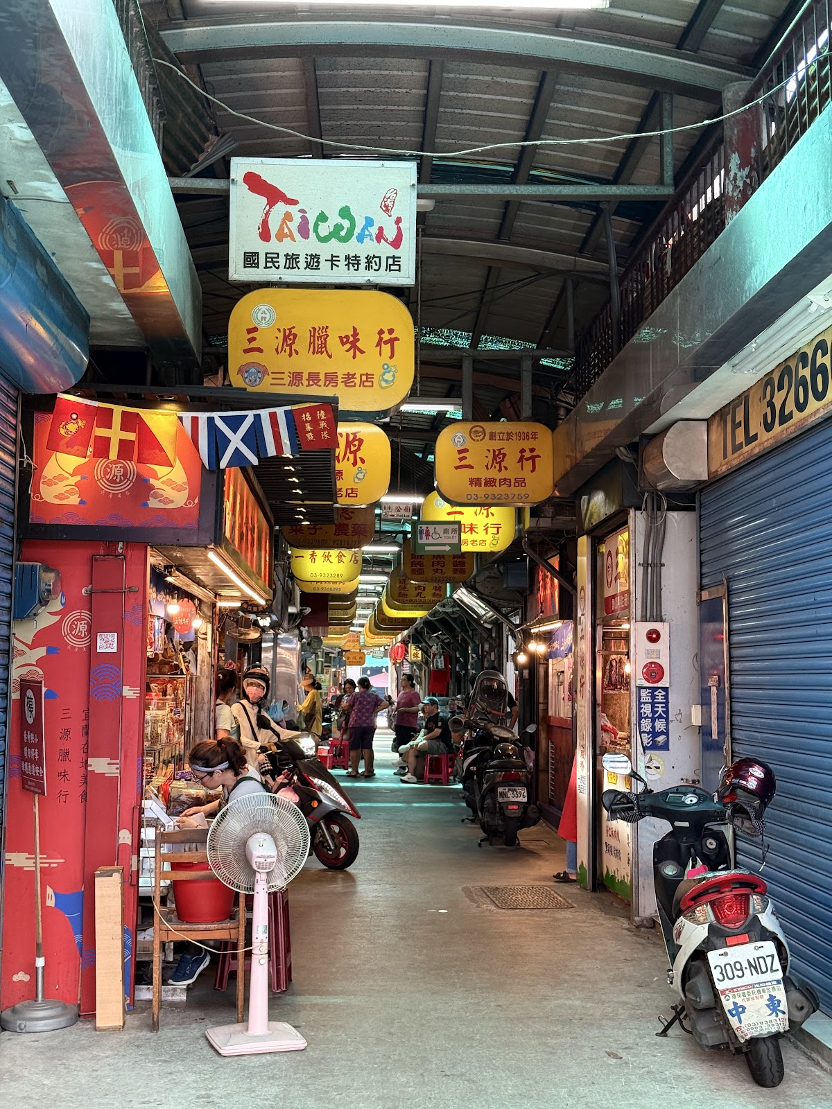 北館市場內的窄巷商店街,兩側店家招牌林立、機車整齊停放