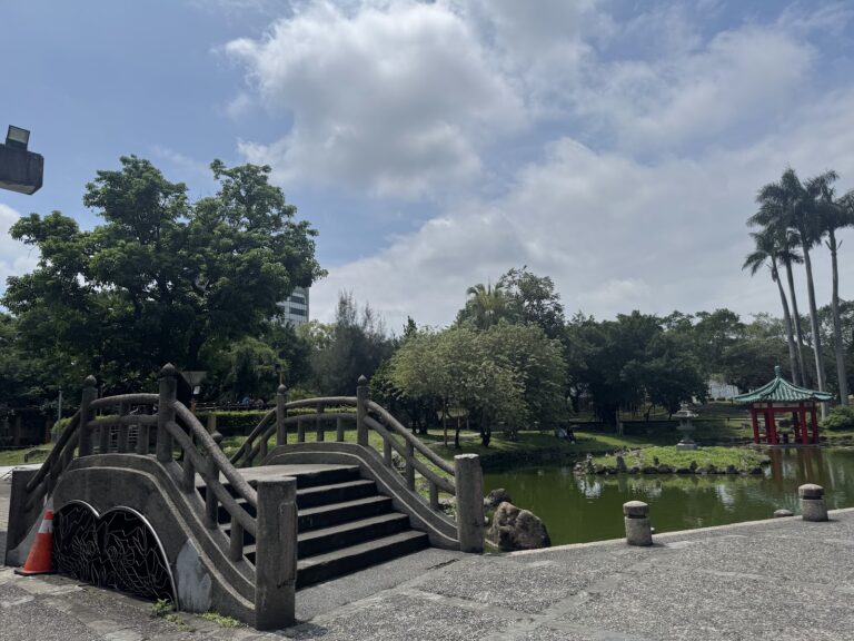 羅東中山公園內的拱形石橋與對岸紅色涼亭,倒映在綠意池水中