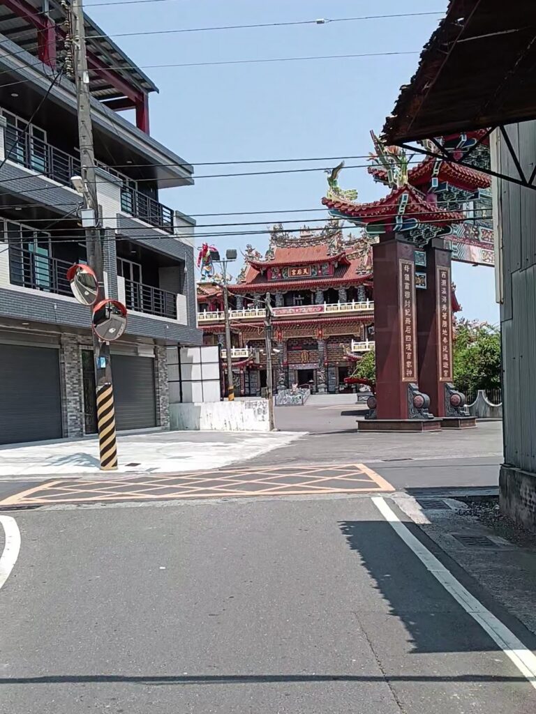 路竹天后宮山門牌樓街景，紅色八角柱與雙龍護頂雕飾矗立巷口