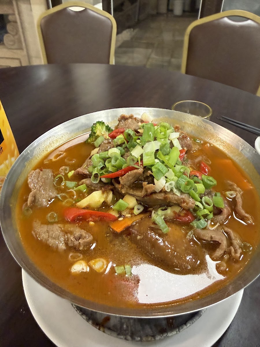 吉祥樓招牌麻辣牛肉鍋特寫，蔥花辣椒鋪滿