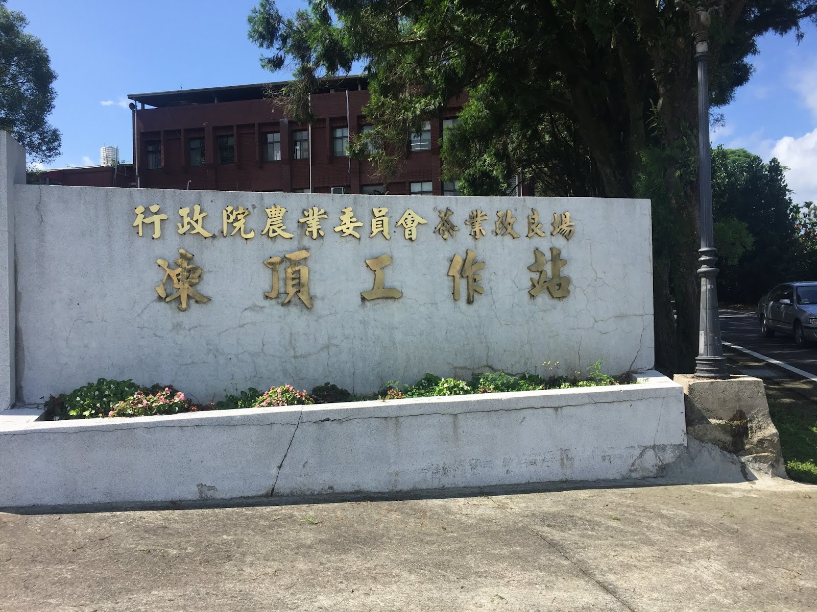 茶改良場南部分場入口圍牆刻字招牌,藍天綠樹環繞