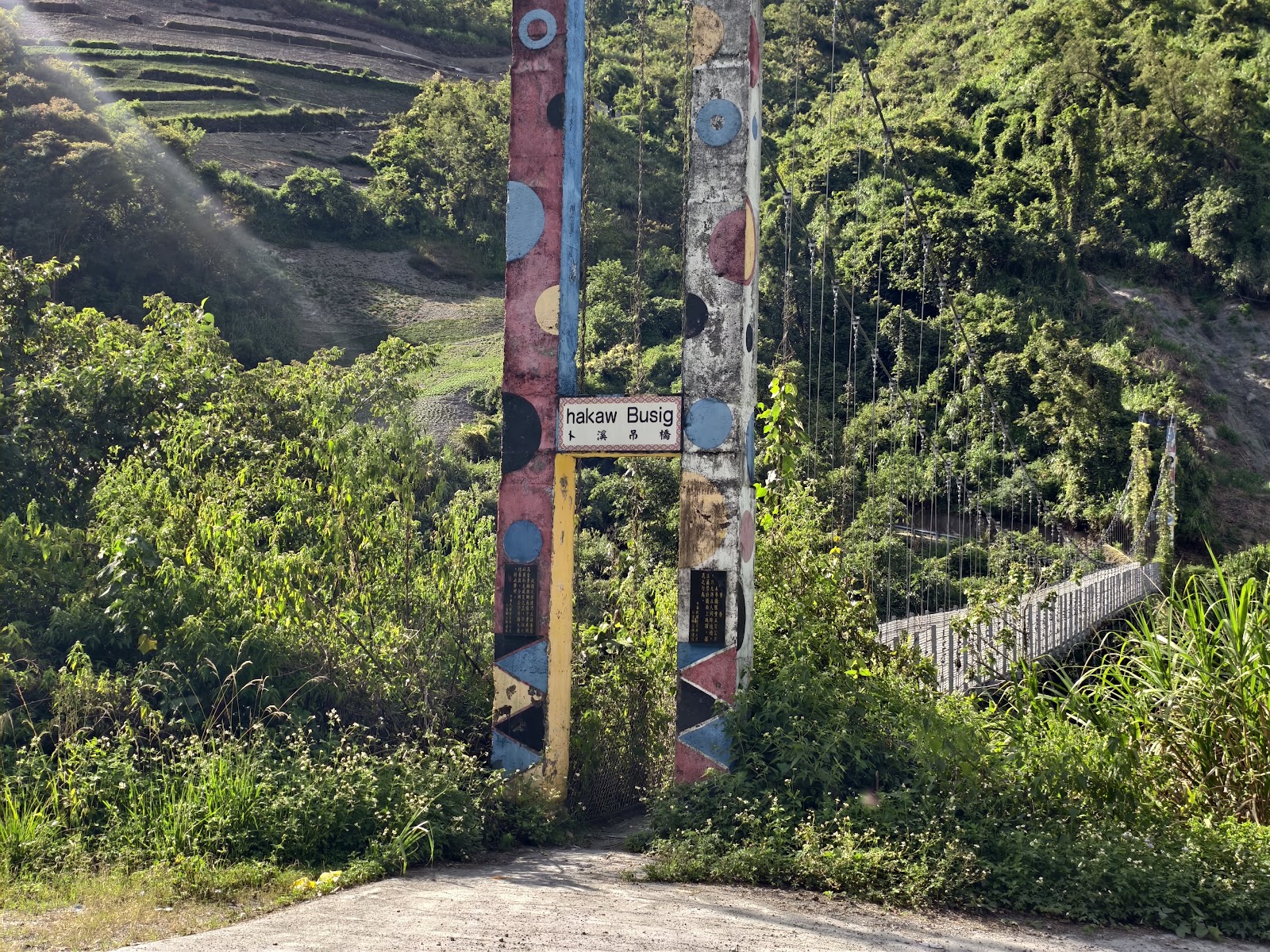 卜溪吊橋入口彩繪圖騰柱，背後吊橋延伸入綠色山谷