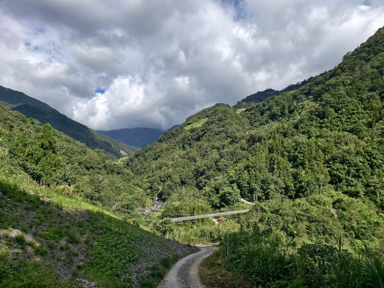 遠景俯瞰卜溪吊橋橫跨深綠色山谷，雲霧繚繞山巒