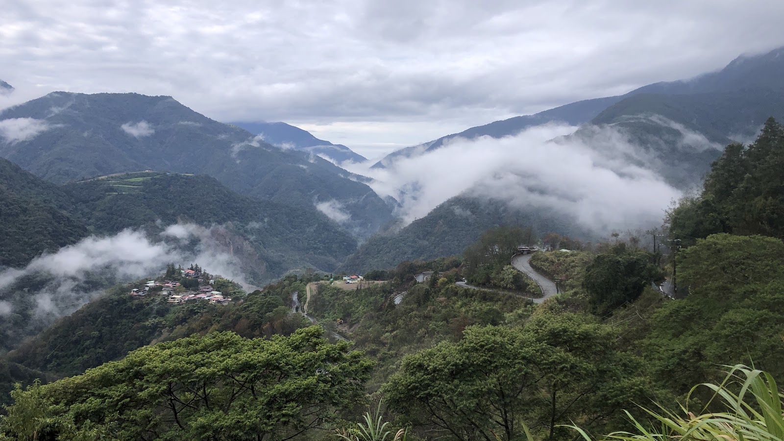 雲海繚繞力行產業道路蜿蜒山徑，部落紅屋頂點綴山谷