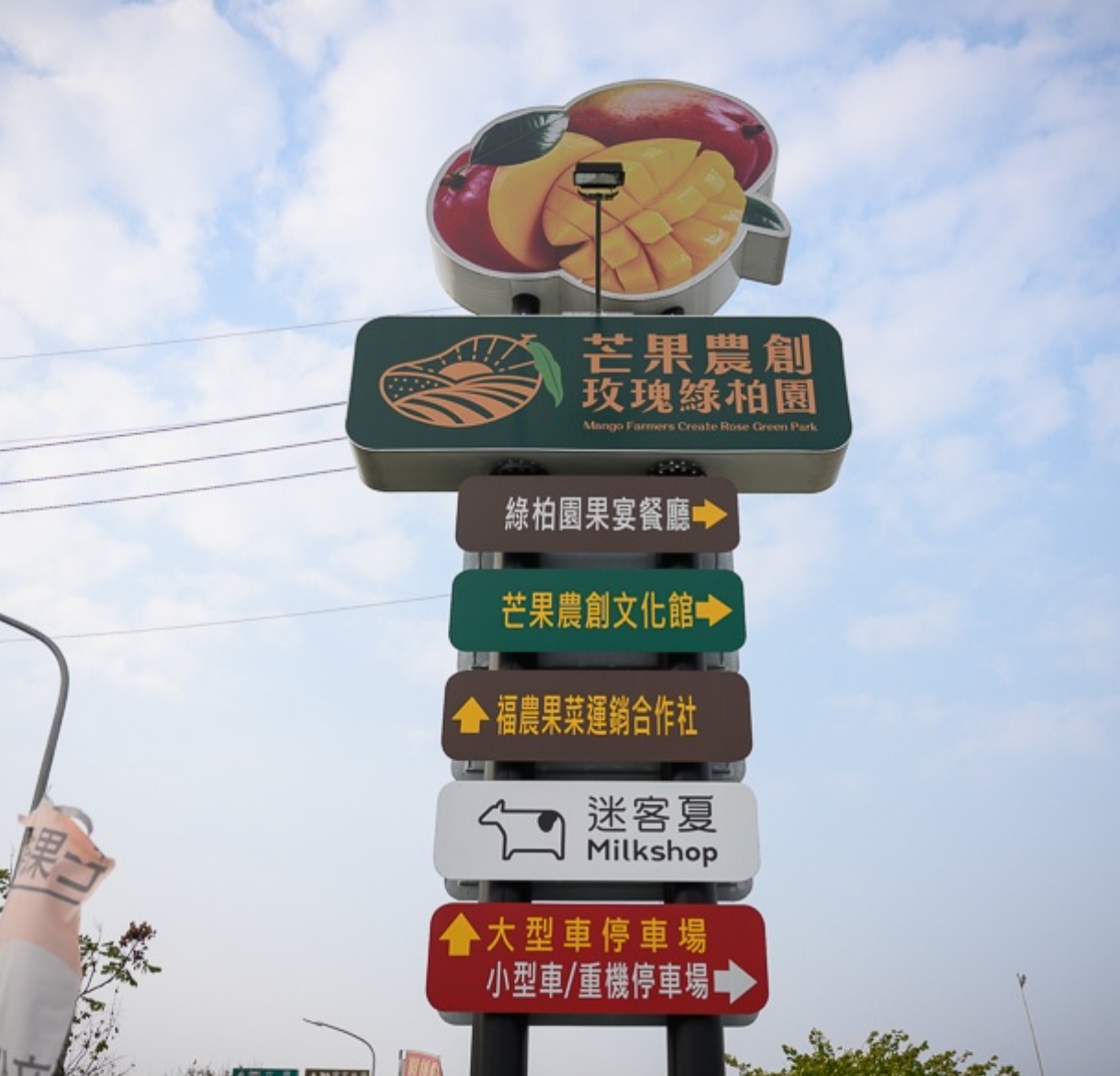 芒果農創玫瑰綠柏園觀光工廠 - 園區入口的多層指標柱,標示著果宴餐廳、文化館與停車場方向