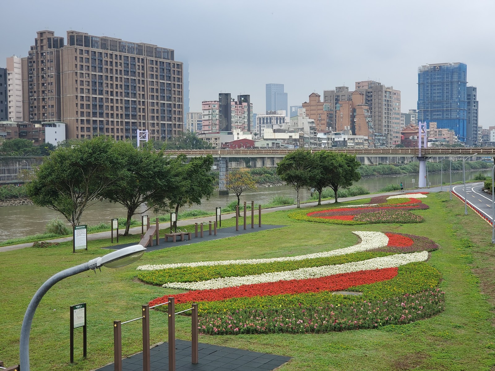 成美右岸河濱公園沿基隆河畔的彩色曲線花圃，背景是台北城市天際線