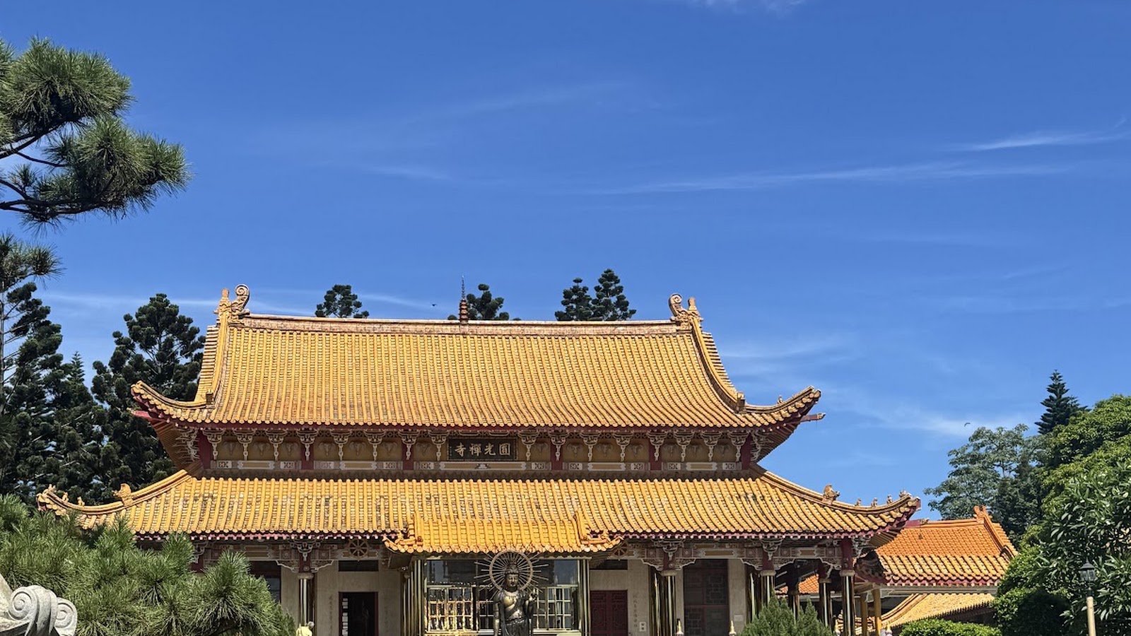 圓光禪寺金黃琉璃瓦大殿屋頂全景，藍天松柏映襯下的牌匾