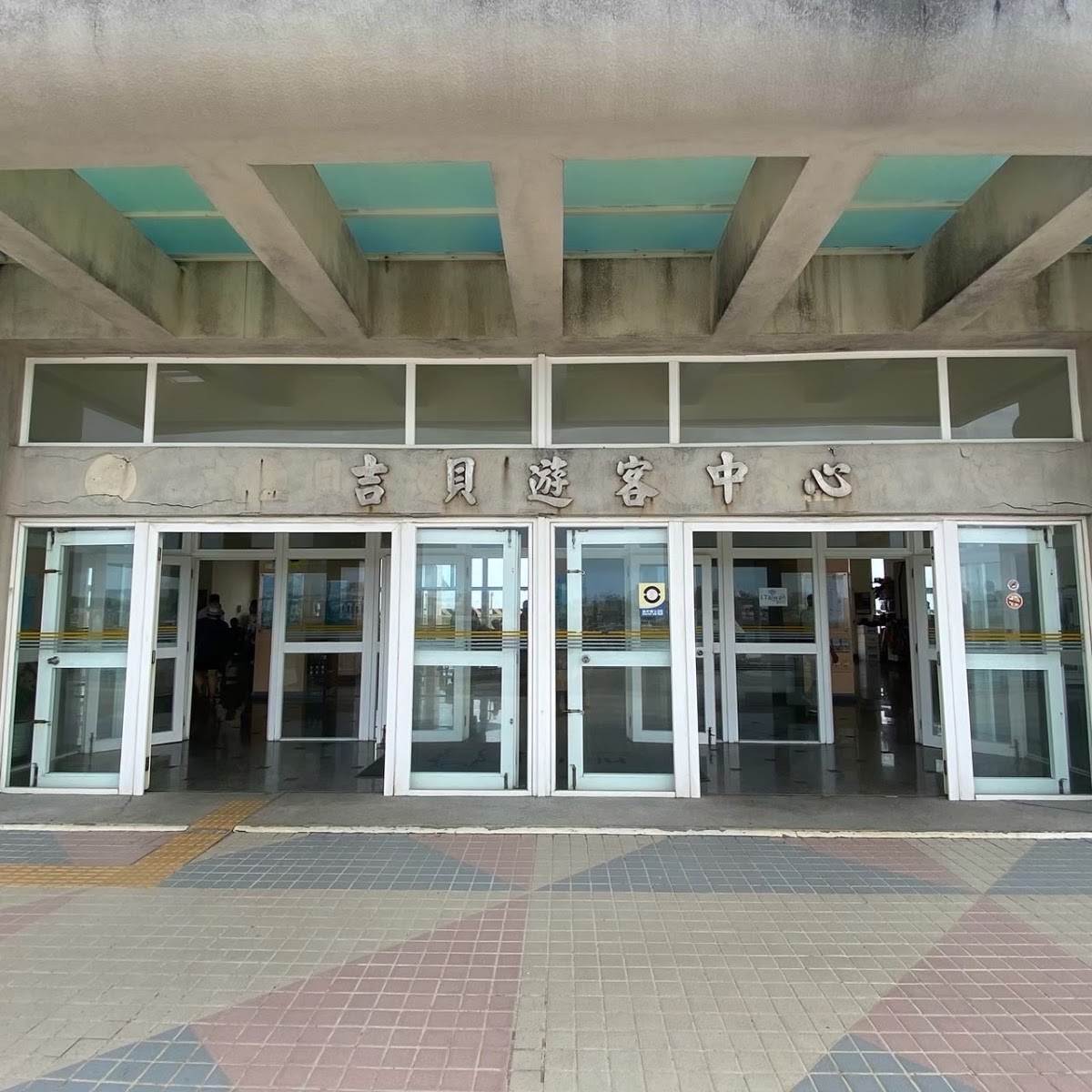全白建築「吉貝遊客中心」招牌入口，玻璃門明亮大方，吉貝旅客服務中心