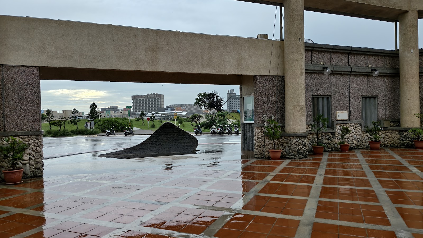 馬公市公所雨後中庭迴廊，紅磚地面映著天光