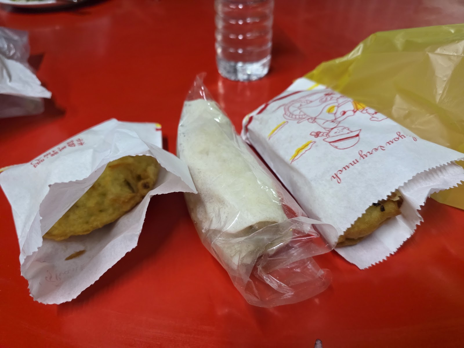 建國炸粿外帶打包的炸粿與潤餅，紙包裝置於紅色餐桌