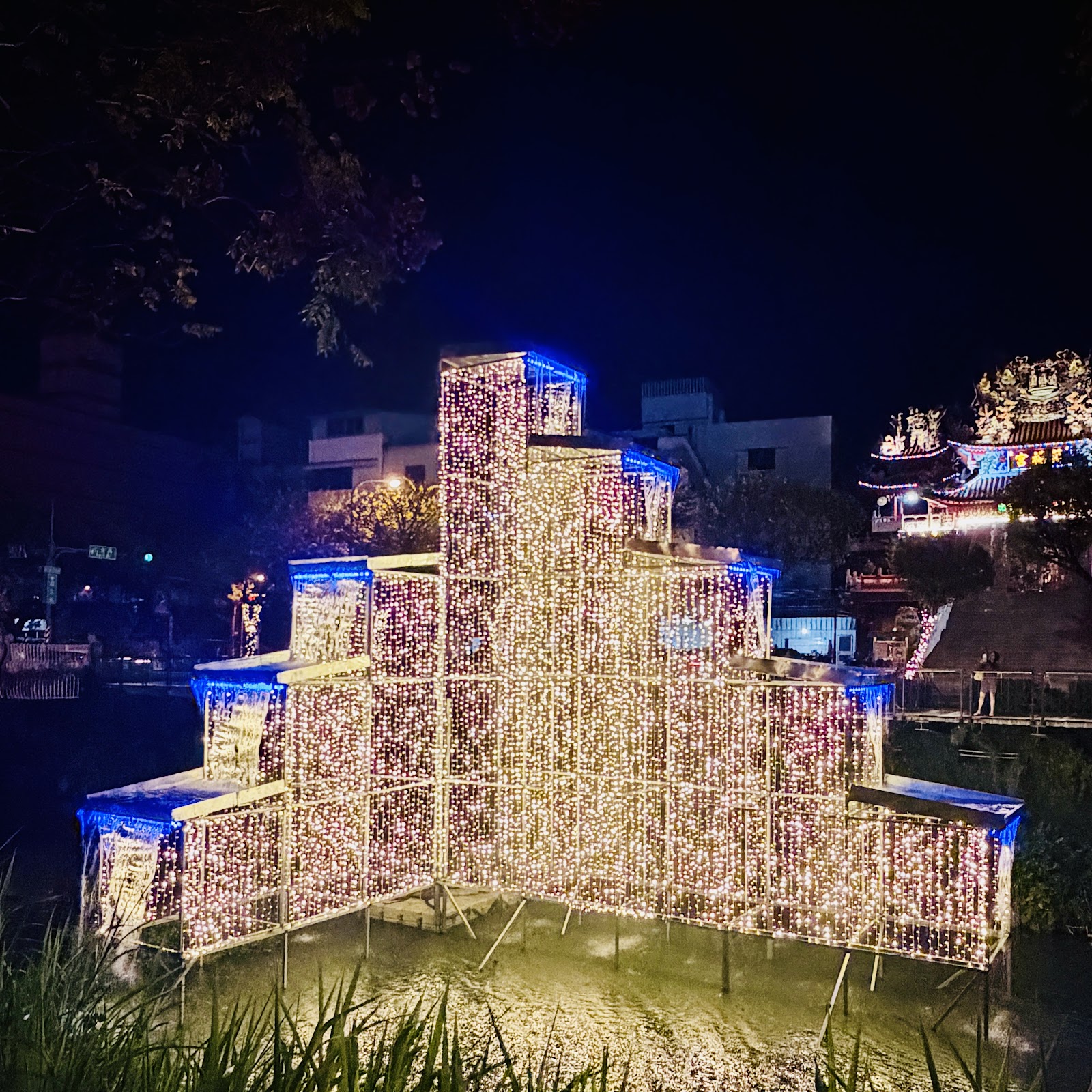 萬年溪夜間燈飾裝置倒映水面與遠景廟宇
