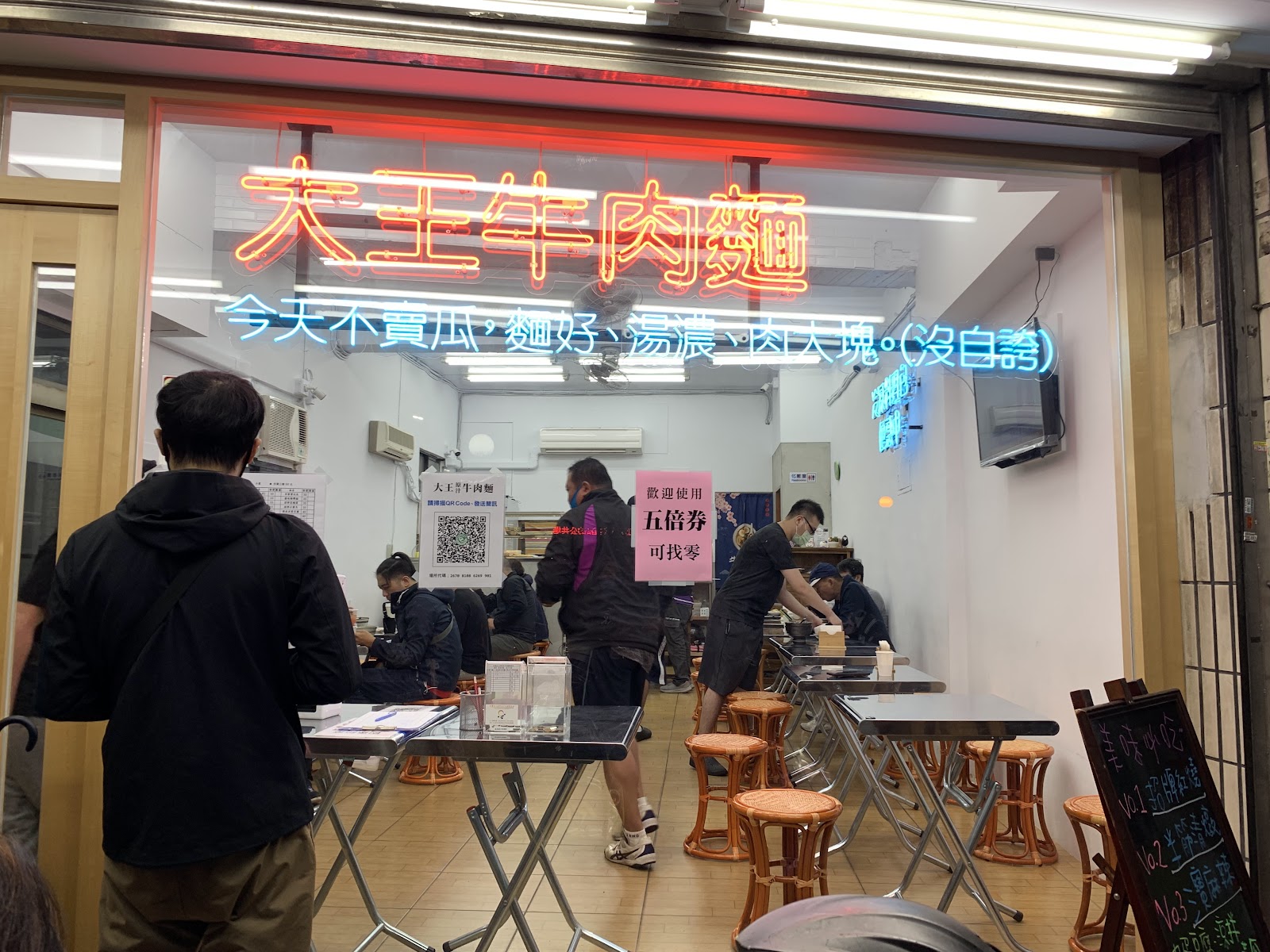 三重力行菜市場內大王牛肉麵店面,紅色霓虹招牌,店內顧客正在排隊點餐