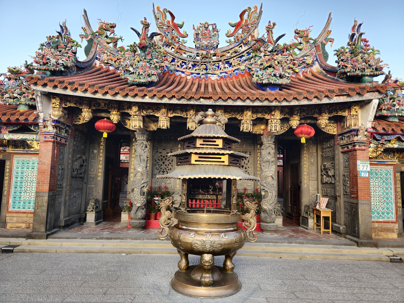 三重先嗇宮廟宇正面外觀,屋頂有精緻龍鳳剪黏裝飾,前方擺放銅製香爐