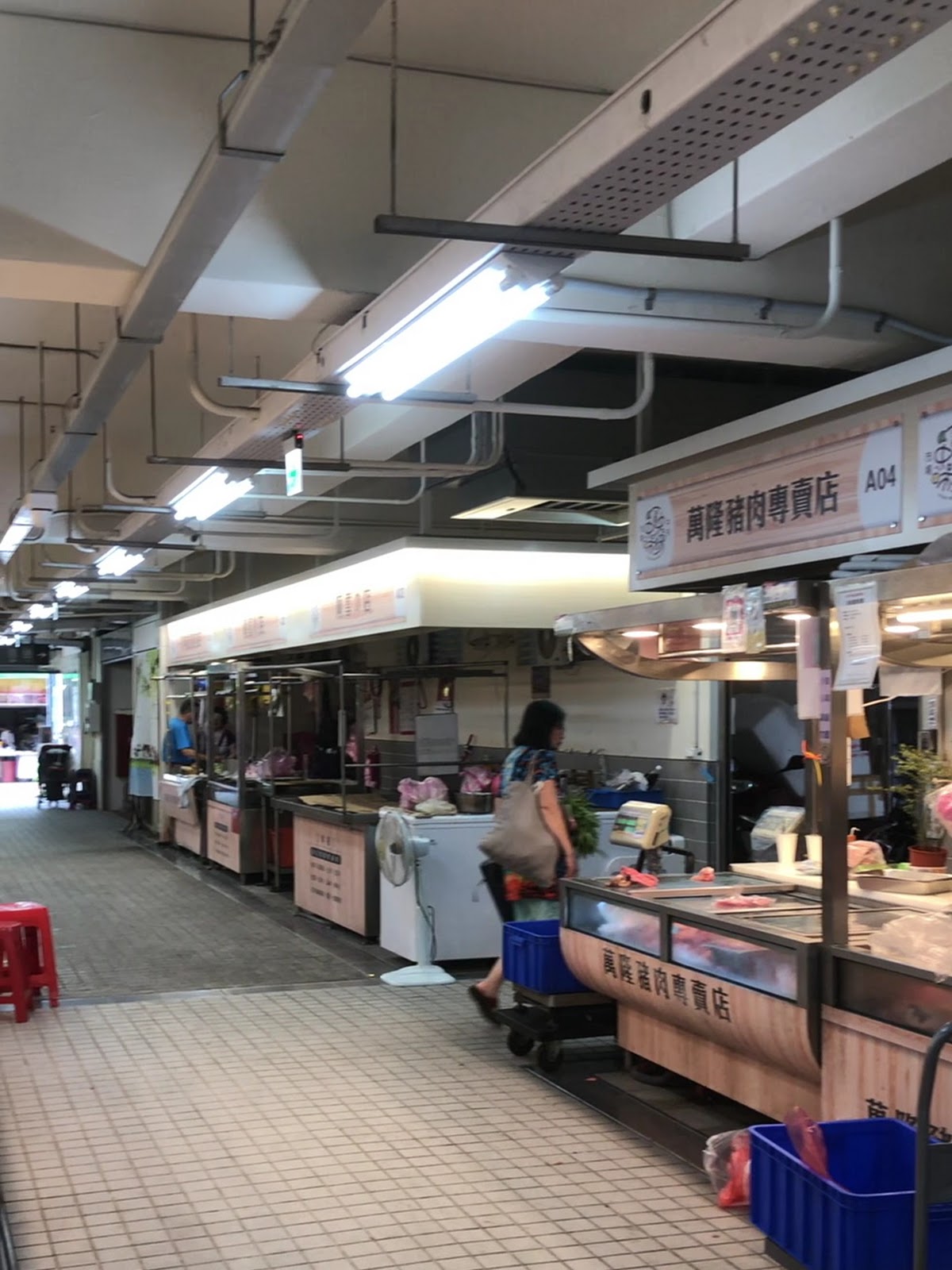 三重中央市場內部走道,明亮現代化裝修,萬隆豬肉專賣店攤位整齊陳列肉品