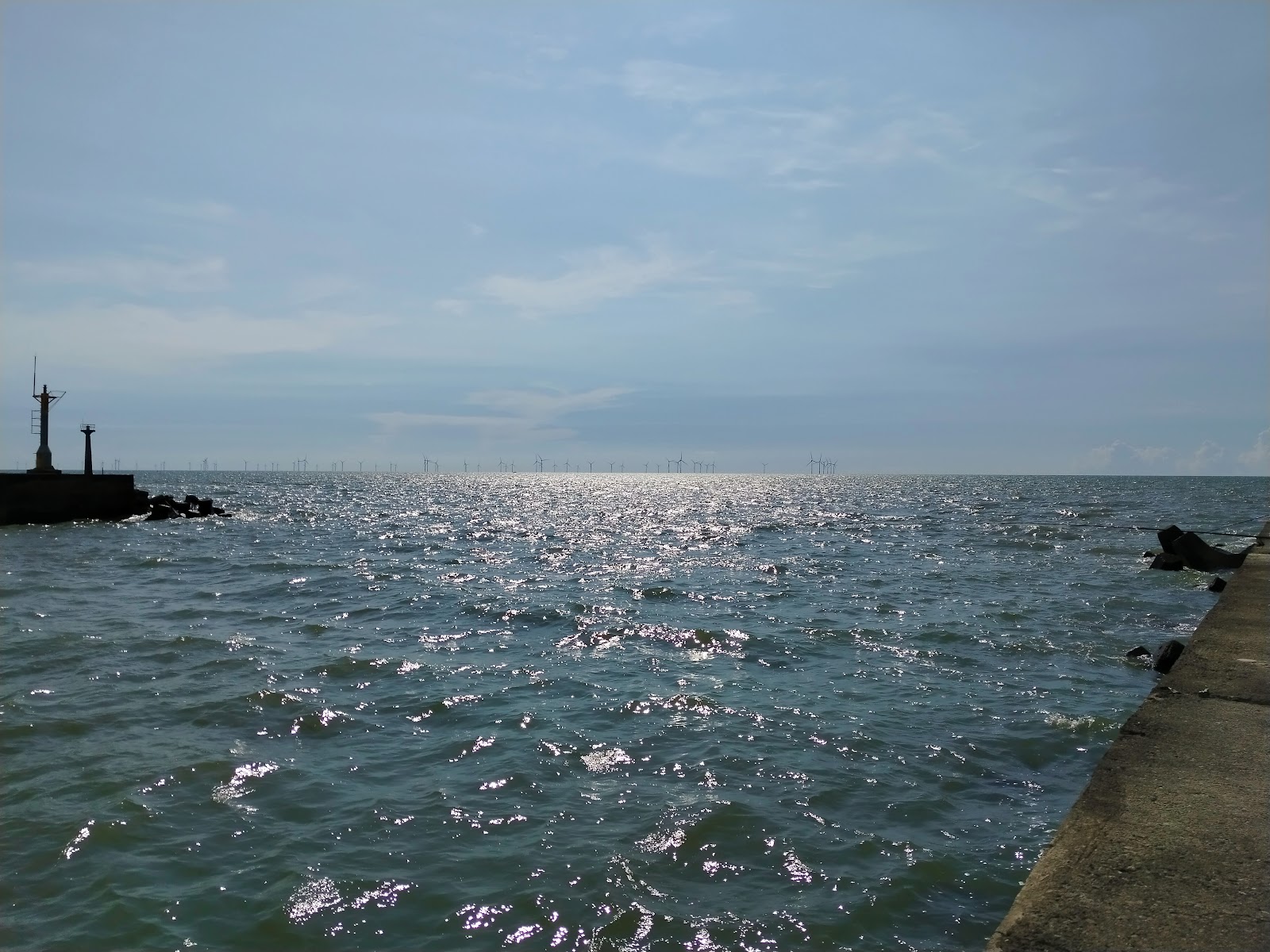 三條崙漁港-出海口燈塔與一整排離岸風機剪影,海面波光