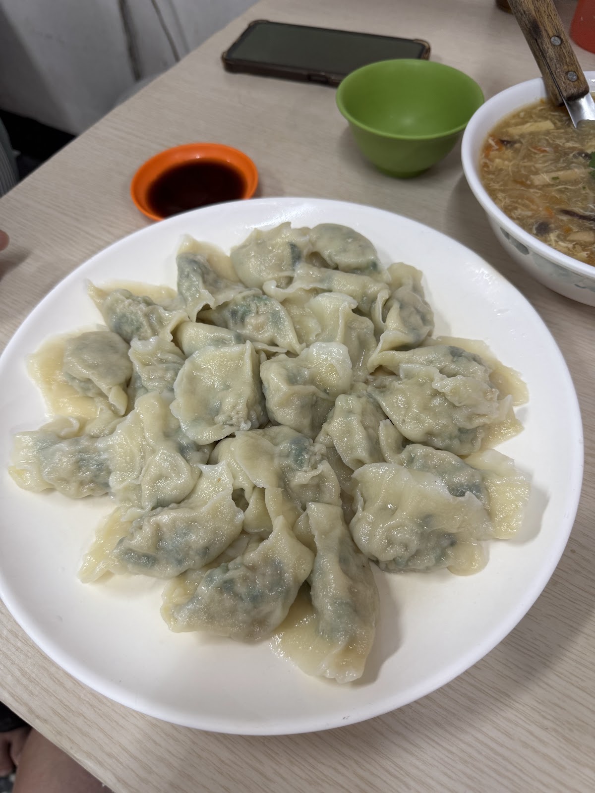 一大盤韭菜豬肉水餃擺盤成花形，配酸辣湯與沾醬
